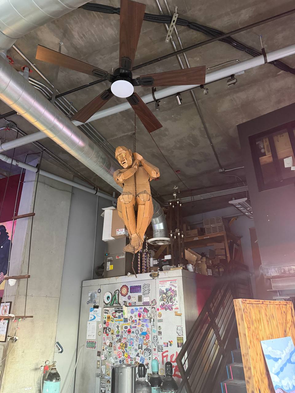 Wooden or Cardboard Sculpture of a man hanging from the ceiling at Jobot Coffee and Bar.